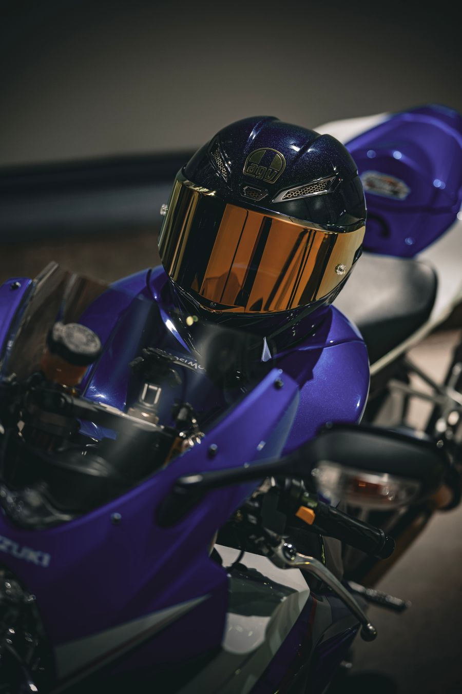 Moto deportiva azul con un casco en el depósito, dentro de un garaje